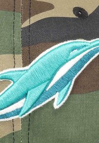 Camo baseball cap featuring an embroidered turquoise dolphin design, detailed with white accents on a textured brown and green background.