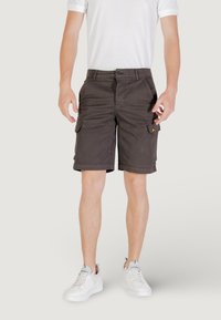 Pantaloni cargo scuri realizzati in tessuto resistente, caratterizzati da due tasche laterali e una tasca sulla gamba destra, con orlo arrotolato e chiusura con bottone.