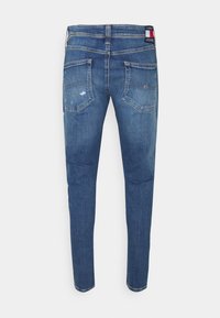 Úzké modré džíny vyrobené z denimu. Obsahují pět kapes, mírné vyblednutí a značkovou nálepku na zadním p�ásku.