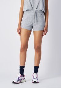 Graue Baumwollmischung-Shorts mit einem elastischen Taillenbund und einer Kordel. Kombiniert mit weißen Sportschuhen und marineblauen Kniestrümpfen mit Logo.