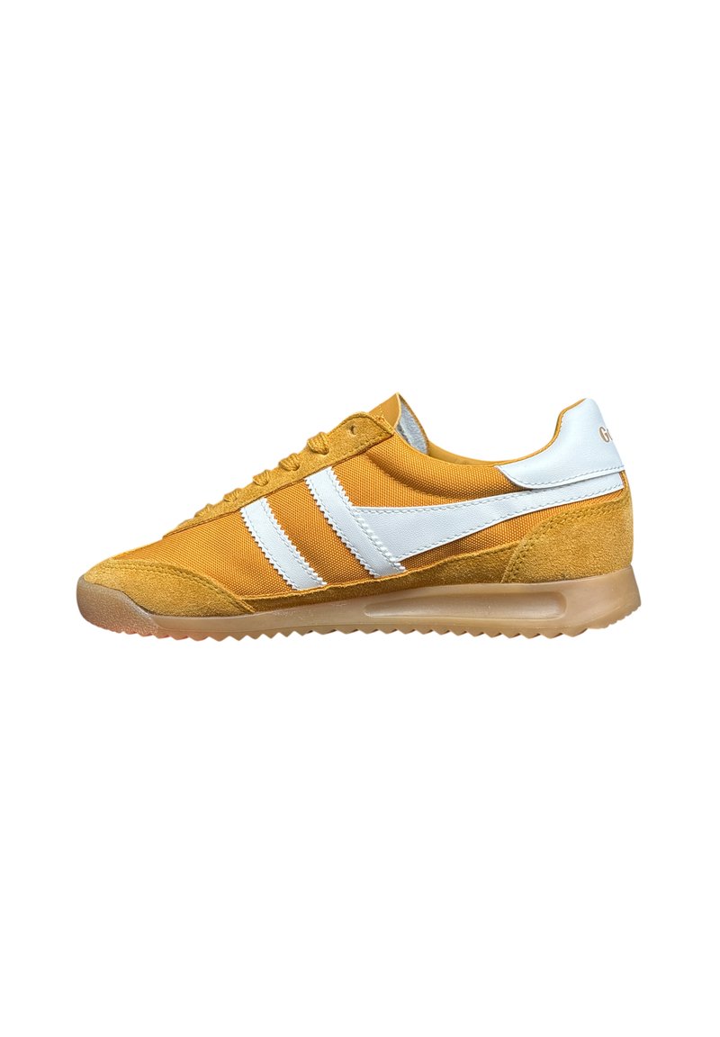 Zapatilla amarilla con parte superior de ante y textil, rayas blancas y suela de goma translúcida. Cuenta con un cuello acolchado para mayor comodidad.