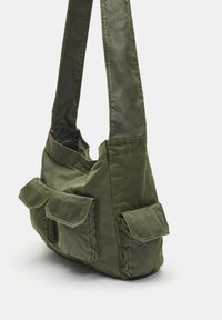 Oliwkowa torba z miękkiego materiału, z dwoma przednimi kieszeniami na klapki i szerokim paskiem. Prosty, funkcjonalny design.