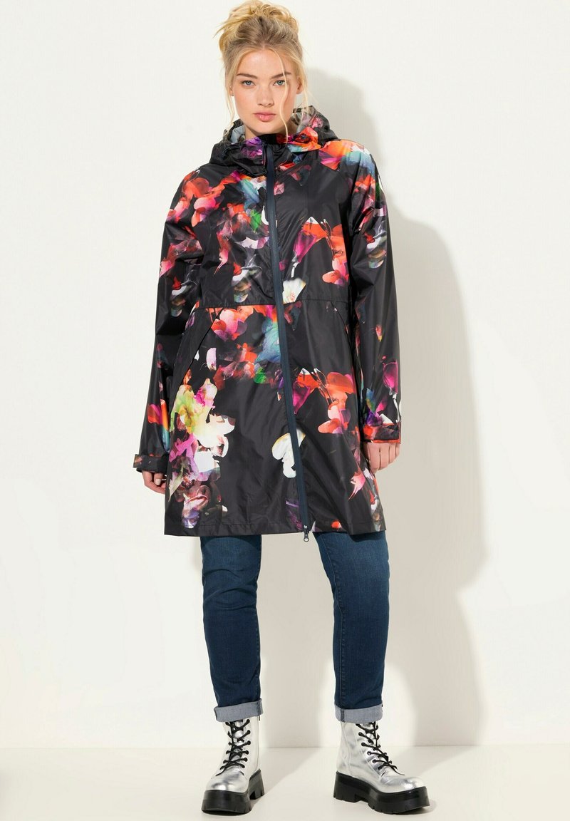 Waterdichte zwarte regenjas met levendige bloempatronen in roze, oranje en wit. Bevat een capuchon, ritssluiting en zakken.