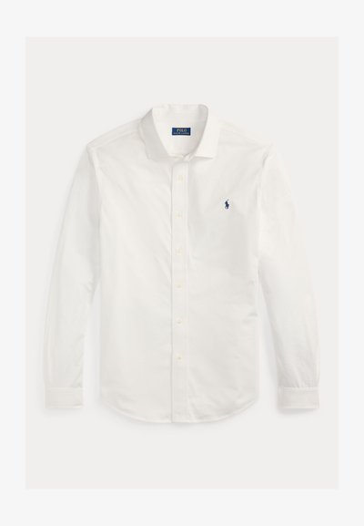 Λευκό μακρύ μανίκι πουκάμισο από βαμβάκι. Διαθέτει γιακά που κουμπώνει, μπροστινή κλείσιμο με κουμπιά και μικρό ναυτικό λογότυπο στο αριστερό στήθος.