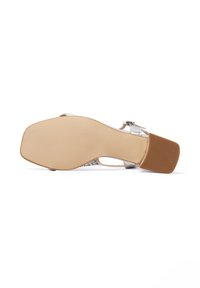 Sandal con tacco argento e suola in gomma marrone texturizzata, pannelli laterali trasparenti e cinturino metallico alla caviglia. Presenta un design con tacco a blocco.