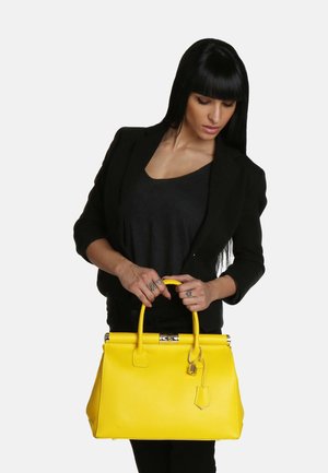 Sac à main en cuir jaune avec un design structuré, des poignées supérieures et un détail de serrure. Le sac présente une surface texturée et des accents en métal argenté.