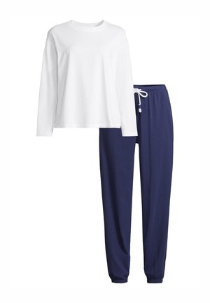Chemise blanche à manches longues associée à un pantalon de jogging bleu marine à cordon, conçu pour un confort décontracté ou détente.