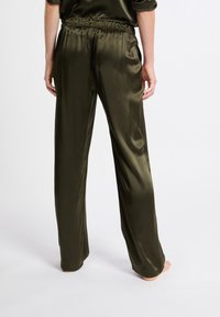 Satijnen olijfgroene broeken met een losse pasvorm, elastische tailleband en taps toelopende benen, die een soepele textuur en minimalistisch ontwerp bieden.