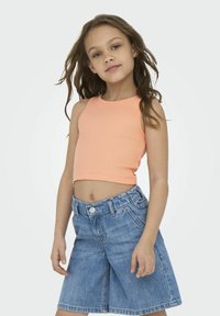 Un débardeur côtelé pêche associé à un short en denim bleu clair, doté d'une taille élastique et d'une fermeture à bouton.