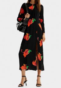 Schwarzes Maxikleid mit langen Ärmeln, das mit bunten Blumenmustern in Rot, Orange und Grün versehen ist. Enthält einen vorderen Schlitz und ein schlichtes Design.