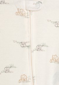 Vasketøj i cremefarvet med lyse elefantillustrationer. Har en frontknaplukning og blød tekstur, der er egnet til spædbørn.