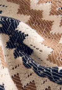 Gewebter Stoff mit einem geometrischen Sternmuster in Braun, Creme und Marineblau. Die Textur ist weich mit einem leichten, offen gewebten Design.