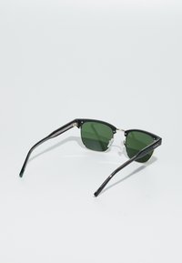 Ochelari de soare negri cu lentile verzi, rame unghiulare și accesorii argintii. Temele texturate cu un design elegant. Material ușor.