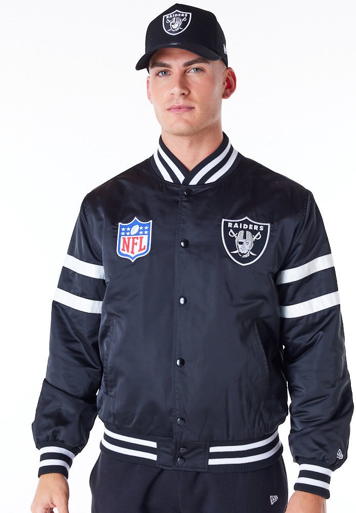 Chaqueta bomber negra con rayas blancas, logotipos de la NFL y de los Raiders. Cuello, puños y dobladillo acanalados. Tejido suave y brillante con forro acolchado.
