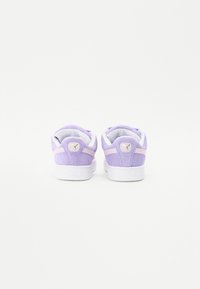 Violet nubuk-tossut valkoisilla yksityiskohdilla, joissa on pehmustettu kaulus ja kieli, logo-yksityiskohta heelissä sekä teksturoitu kumipohja.