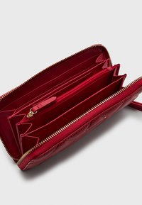 Sarkans quiltots maks, kas izgatavots no sintētiska materiāla, ar vairākiem nodalījumiem, ar rāvējslēdzēju nodalījumu un zelta tonī rāvējslēdzēju aparatūru.