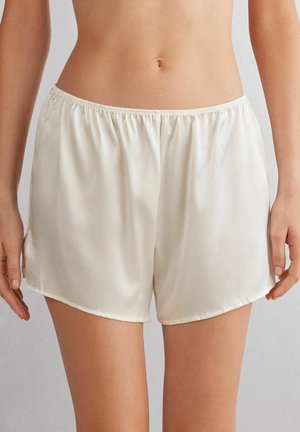 Silkiga, krämfärgade shorts med resårmidja, som har en slät yta och en subtil glans, skurna ovanför låret med rundade fållar.