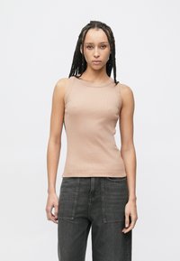 Beiger Rippstrick-Panzer-Top mit rundem Ausschnitt, figurbetonter Silhouette und ärmellosem Design, kombiniert mit dunkelgrauen Jeans mit weitem Bein.