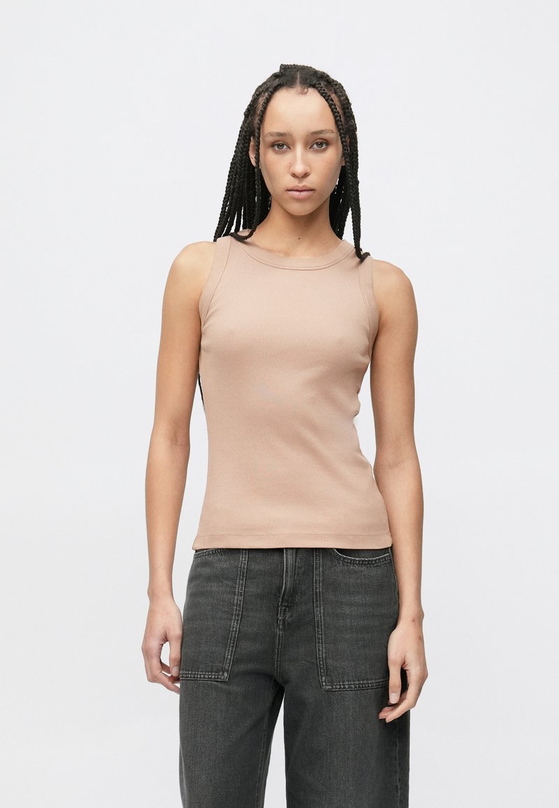 Beiger Rippstrick-Panzer-Top mit rundem Ausschnitt, figurbetonter Silhouette und ärmellosem Design, kombiniert mit dunkelgrauen Jeans mit weitem Bein.