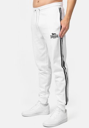 Pantalon de sport blanc avec des bandes latérales noires, taille élastique et logo Lonsdale sur la jambe gauche. Fabriqué en tissu doux, idéal pour un look décontracté.