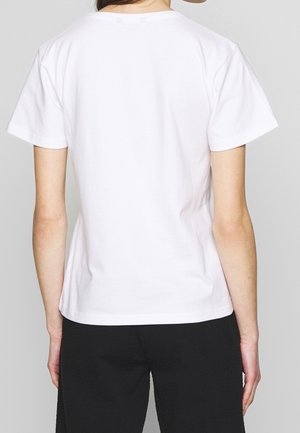 Maglietta bianca in cotone con maniche corte e scollo rotondo, caratterizzata da una texture liscia e un design semplice. Nessun logo o motivo visibile.