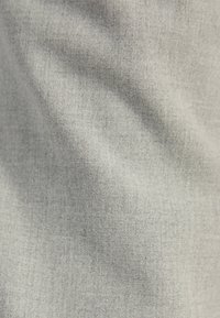 Ljust grått tyg med en mjuk yta och ett subtilt mönster. Det visar på lätta veck och är välstrukturerat, lämpligt för textilanvändning.