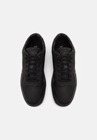 Sneakers neri con tomaia in pelle liscia, punta arrotondata, design con lacci e suola in gomma testurizzata. Presenta un dettaglio del logo sulla linguetta.