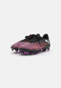 Black football boots with a textured upper featuring a purple and orange zigzag pattern. The boot has purple studs and black laces.