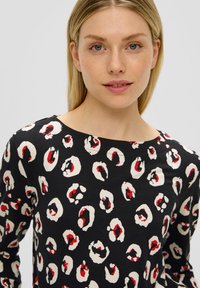 Schwarzes Langarmoberteil mit einem Leopardenmuster in Rot und Creme. Runder Ausschnitt und glatte Stoffstruktur.