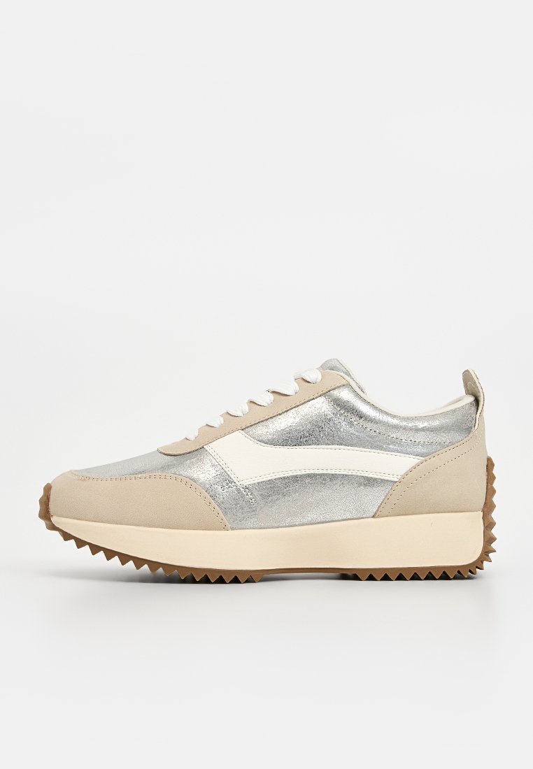 Sneakers con una toma metallic silver, dettagli bianchi ai lati, dettagli in suede beige e una suola in gomma testurizzata con motivo a zigzag.