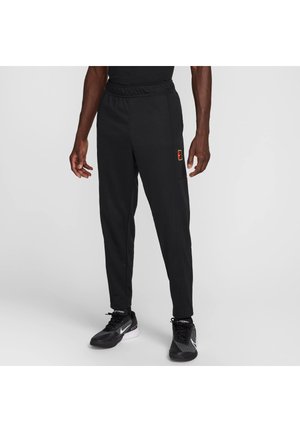 Pantalon de sport noir avec une ceinture élastique, jambes fuselées, et un petit logo multicolore sur la cuisse ; texture de tissu lisse.