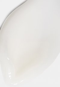 Crème ou lotion blanche étalée sur une surface blanche avec une texture douce, brillante et des bords arrondis.