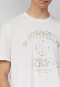 Weißes Baumwoll-T-Shirt mit einem verblassten Grafikdruck, der "AWESOME SUNNYDAYS" und "WAVES UNLIMITED" zeigt. Kurze Ärmel und Rundhalsausschnitt.