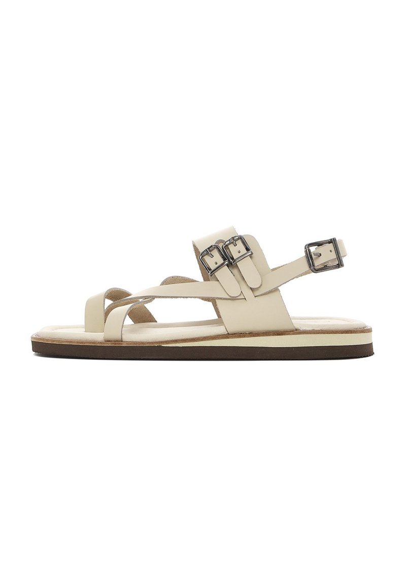 Beige leren sandaal met meerdere bandjes, voorzien van twee verstelbare metalen gespen. Platte zool met een contrasterende bruine rand en een zachte binnenzool.