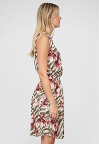 Robe à imprimé floral avec taille élastique ; présente des fleurs roses et bordeaux sur un motif zigzag olive et blanc ; design sans manches.