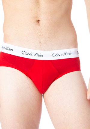 Short en coton rouge avec une taille blanche portant le logo "Calvin Klein" imprimé en noir. Le design comprend un devant sculpté et une couverture minimale.