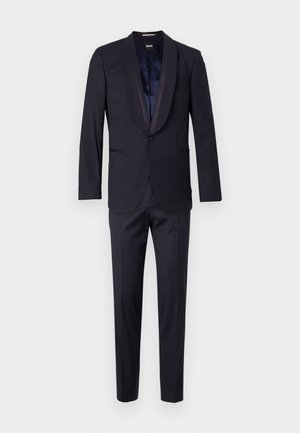 Merine sinine kaheosaline ülikond, millel on märk-lapels, ühe nööbiga kinniti ja sujuvad püksid. Sile kangas kerge läikega; minimalistlik disain.