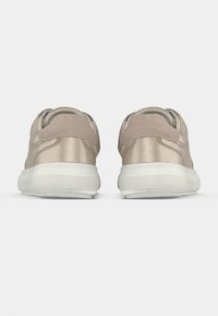 Ζευγάρι μπεζ χαμηλά sneakers με λευκές σόλες, φωτογραφημένα από πίσω σε απλό ανοιχτό φόντο.