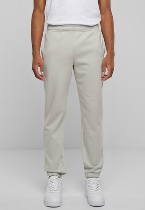 Light grey jogger pants made of soft fabric with an elastic waistband and cuffs, paired with white sneakers. Simple design, no visible patterns.
