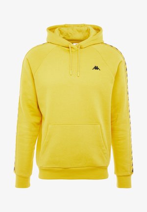Sweat à capuche jaune avec poche avant, cordons de serrage, logo noir sur la poitrine et rayures à motifs le long des deux manches.