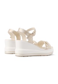 Sandali con tacco a cuneo beige con accenti metallici, design open toe, cinturino alla caviglia con fibbia e suola platform bianca texturizzata.