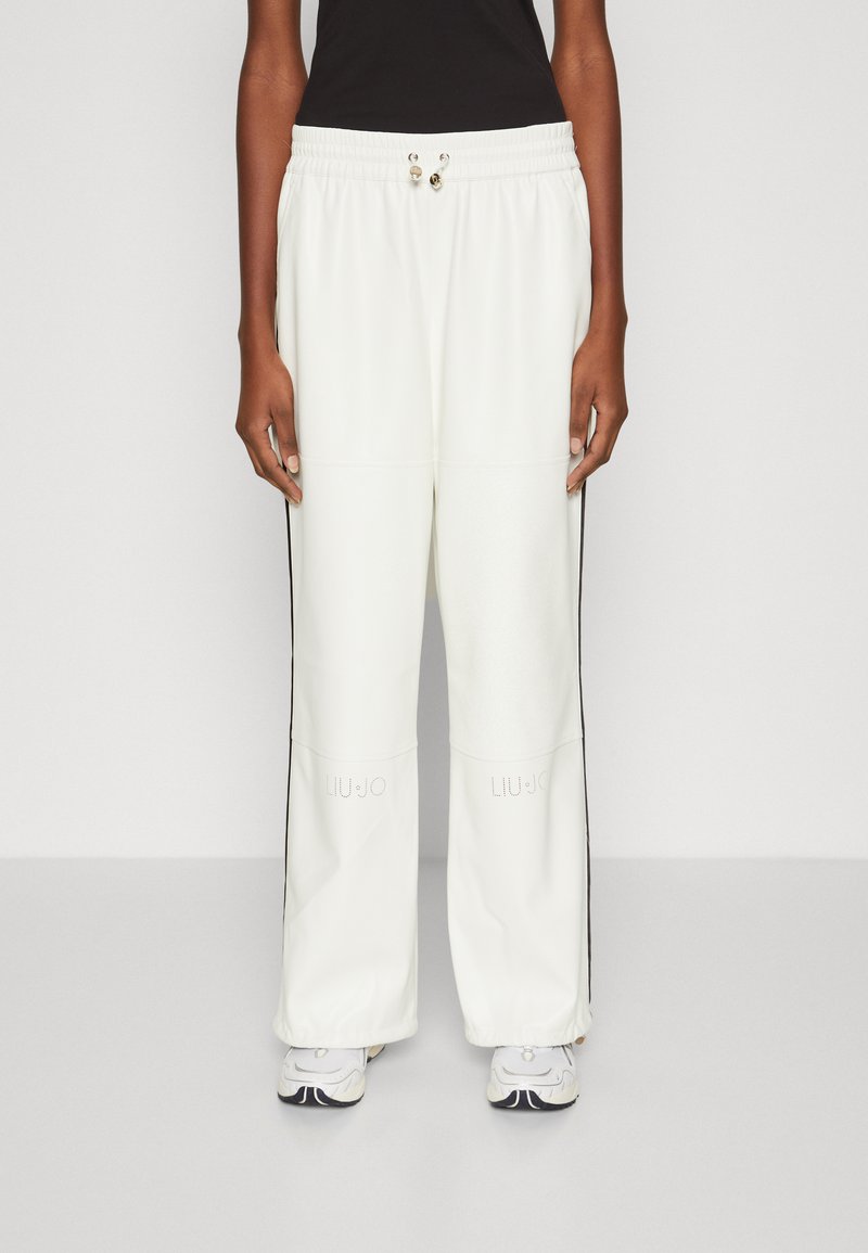 Pantalones de chándal blancos y holgados con rayas laterales negras, con cintura elástica ajustable y logo "LIU JO" cerca del dobladillo inferior.