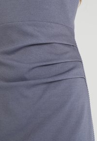 Graues, tailliertes Kleid mit gerafften Falten entlang der Taille, aus einem weichen, strukturierten Stoff mit glatter Oberfläche.