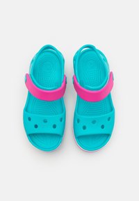 Modré a růžové dětské sandály vyrobené z měkké gumy, s páskem, ventilačními otvory a strukturovanou stélkou pro lepší přilnavost.