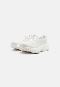 Paire de chaussures de course athlétiques blanches avec des semelles texturées et des tiges en maille, montrées en angle sur un fond blanc uni.