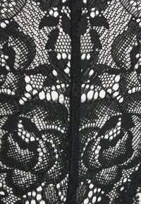 Țesătură din dantelă neagră cu modele florale complicate și textură transparentă. Pare delicată, cu o secțiune solidă contrastantă în mijloc.