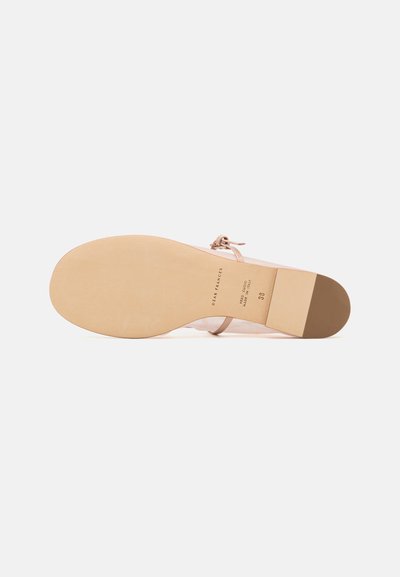 Beige sandal with a smooth leather upper, thin strap, and flat sole. The sole features a cream rubber texture and a block heel accent.