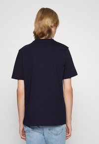 Granatowa bawełniana koszulka z krótkim rękawem i luźnym krojem. Posiada okrągły dekolt i prosty dół. Minimalistyczny design bez widocznych logo.