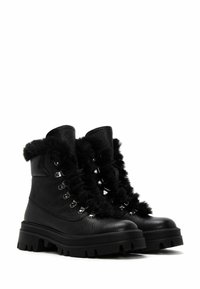 Botas de cuero negro con un acabado texturizado, suelas de goma gruesas, ribete de piel sintética y ojales de metal para los cordones.