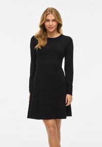 Rochie neagră cu mâneci lungi, dintr-un material neted și elastic. Siluetă A-line cu decolteu rotund și cusături îngrijite la tiv.